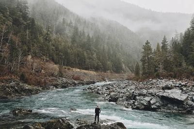man standing jagged rocks fast-flowing. poster print