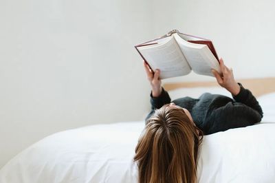 Woman reading book her bed. poster print