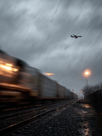 Train and Airplane in Rainy Landscape Poster.